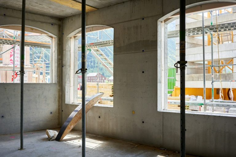 Fenster- und Türöffnung Bauinterieur mit Fenster, Säulen und Sicht auf eine Baustelle im Hintergrund.