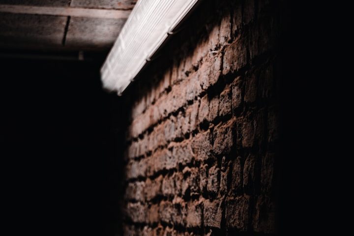 Kellerwand aus Ziegeln Dunkle Ziegelwand mit Lichtreflexion von einer Deckenleiste.